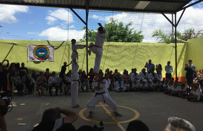 En la demostración los participantes realizan patadas con el apoyo de sus compañeros.